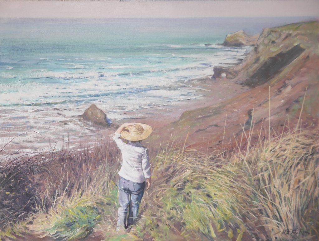 A young woman enjoying her walk along a Cornish cliff